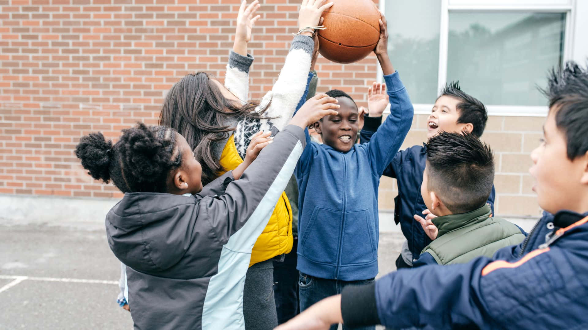 Best Sports 桌布 壁紙 — 孩子們在充滿活力的戶外校園遊戲中跳躍並伸手去拿籃球。