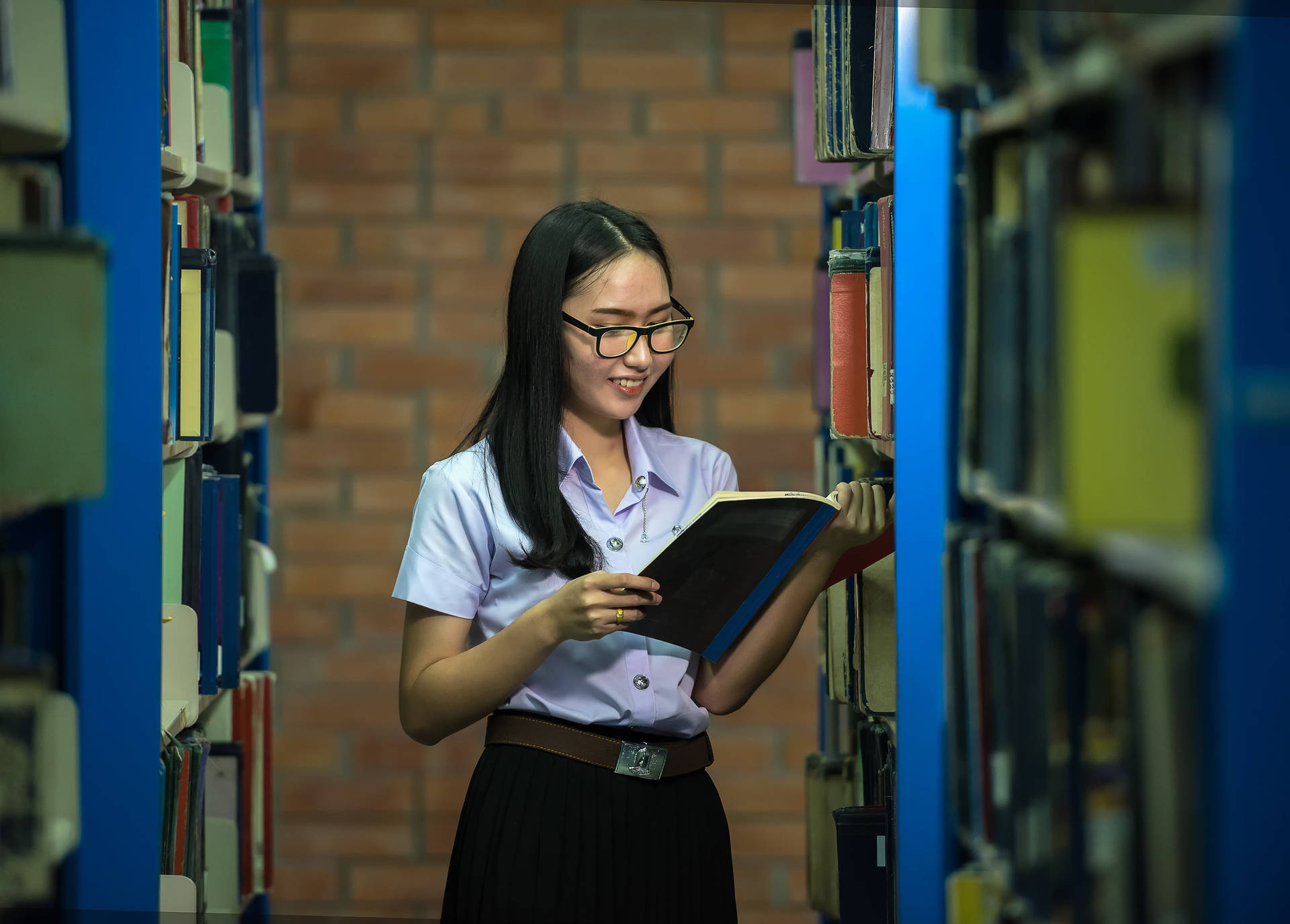 學生在圖書館通道閱讀書籍，磚牆背景