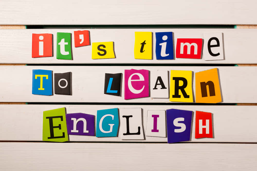 學習英語的木板圖畫 壁紙 — 彩色磁石字母在白色木質表面上拼出「是時候學習英語了」。