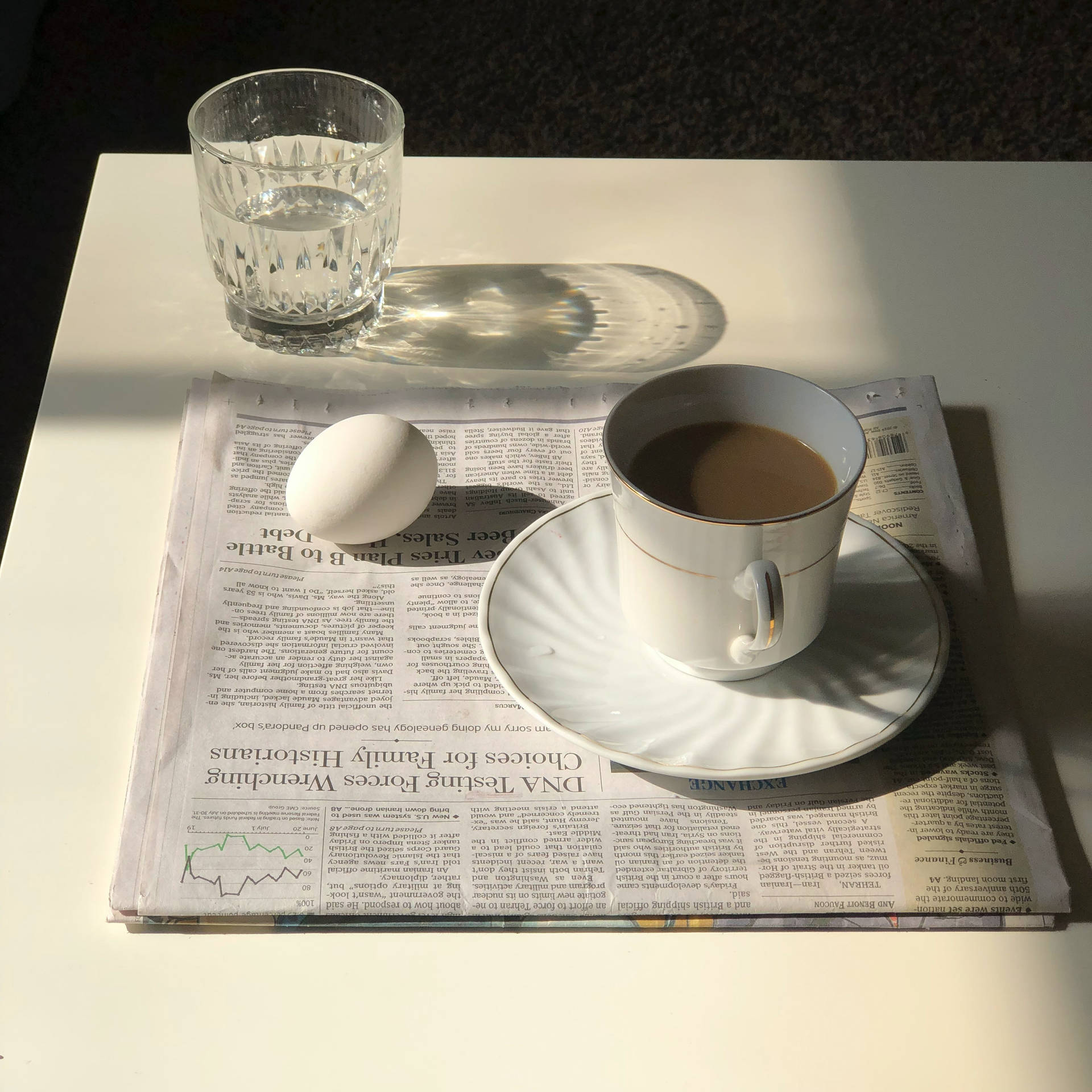 一個玻璃杯放在白色表面上摺疊的報紙上。