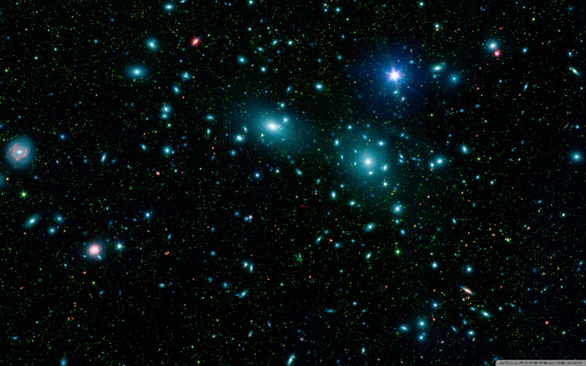 一片密集的星星和星系，在黑色太空中閃耀著藍色和綠色。
