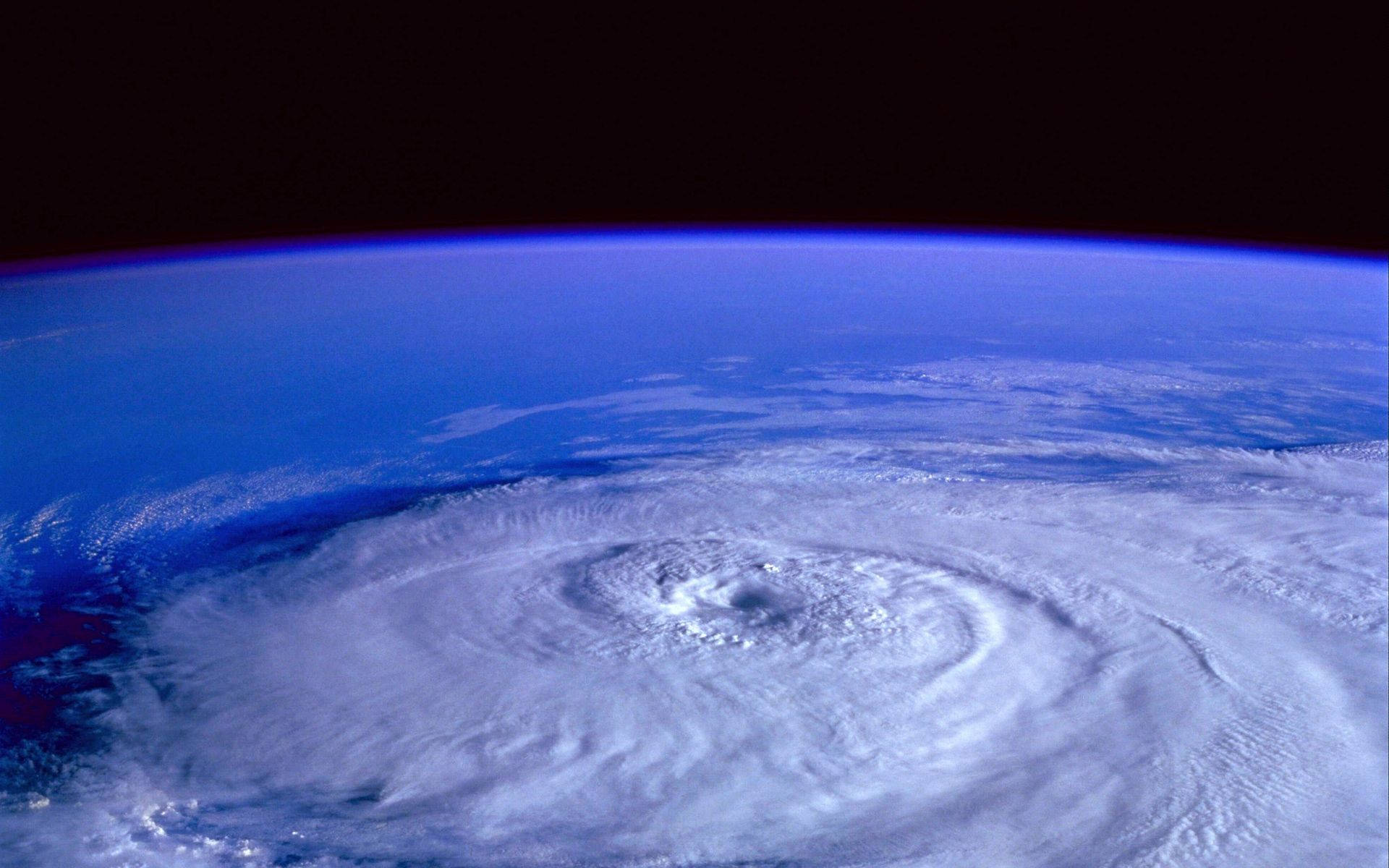 宇宙空間中的颶風 壁紙 — 從太空看到一個巨大颶風在地球的藍色曲線上旋轉，上方是黑暗的虛空。