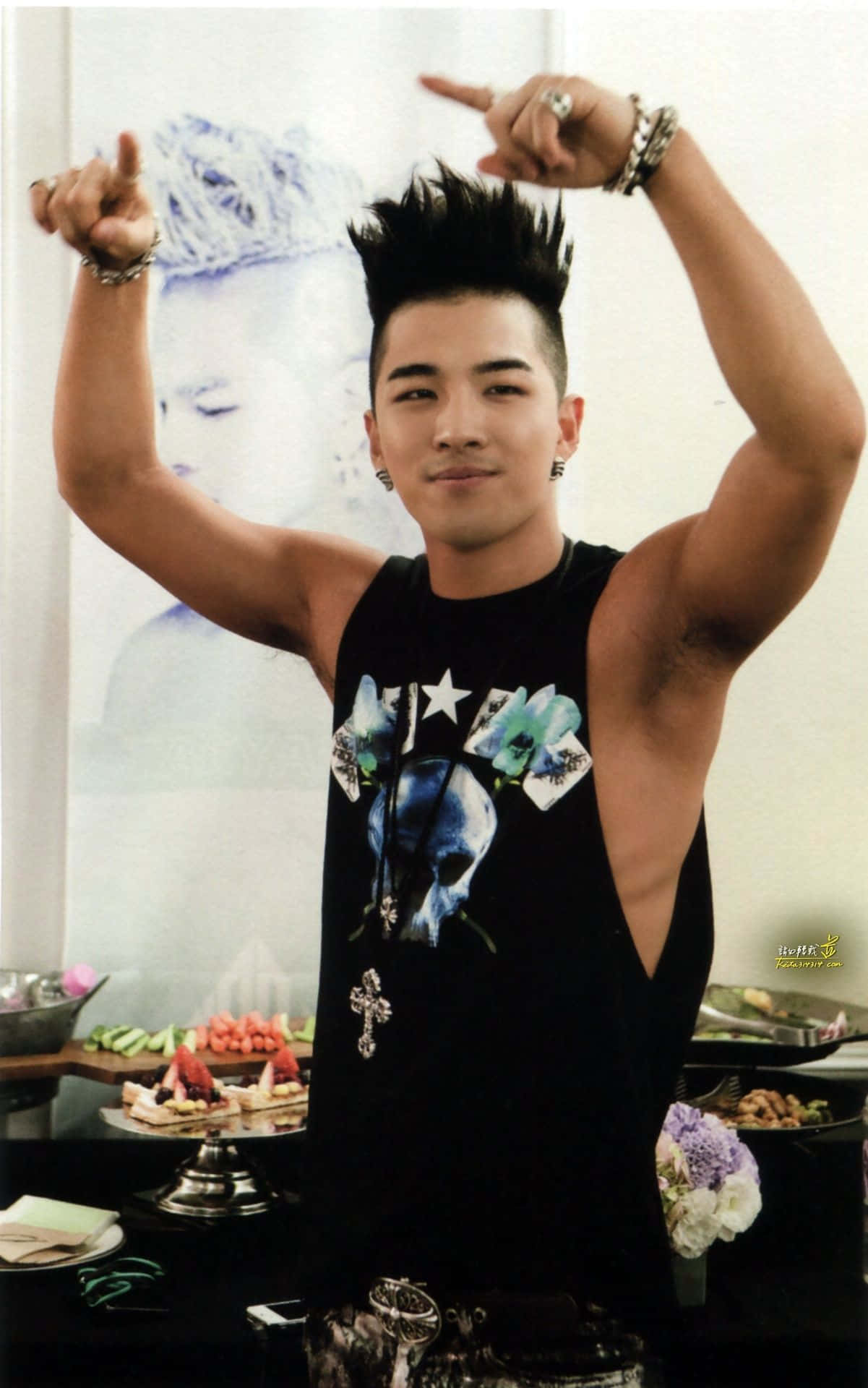 宇宙膨脹的圖解說明 壁紙 — 一位頭髮豎起、有紋身的年輕男子自信地在自助餐桌上穿著黑色背心擺姿勢。