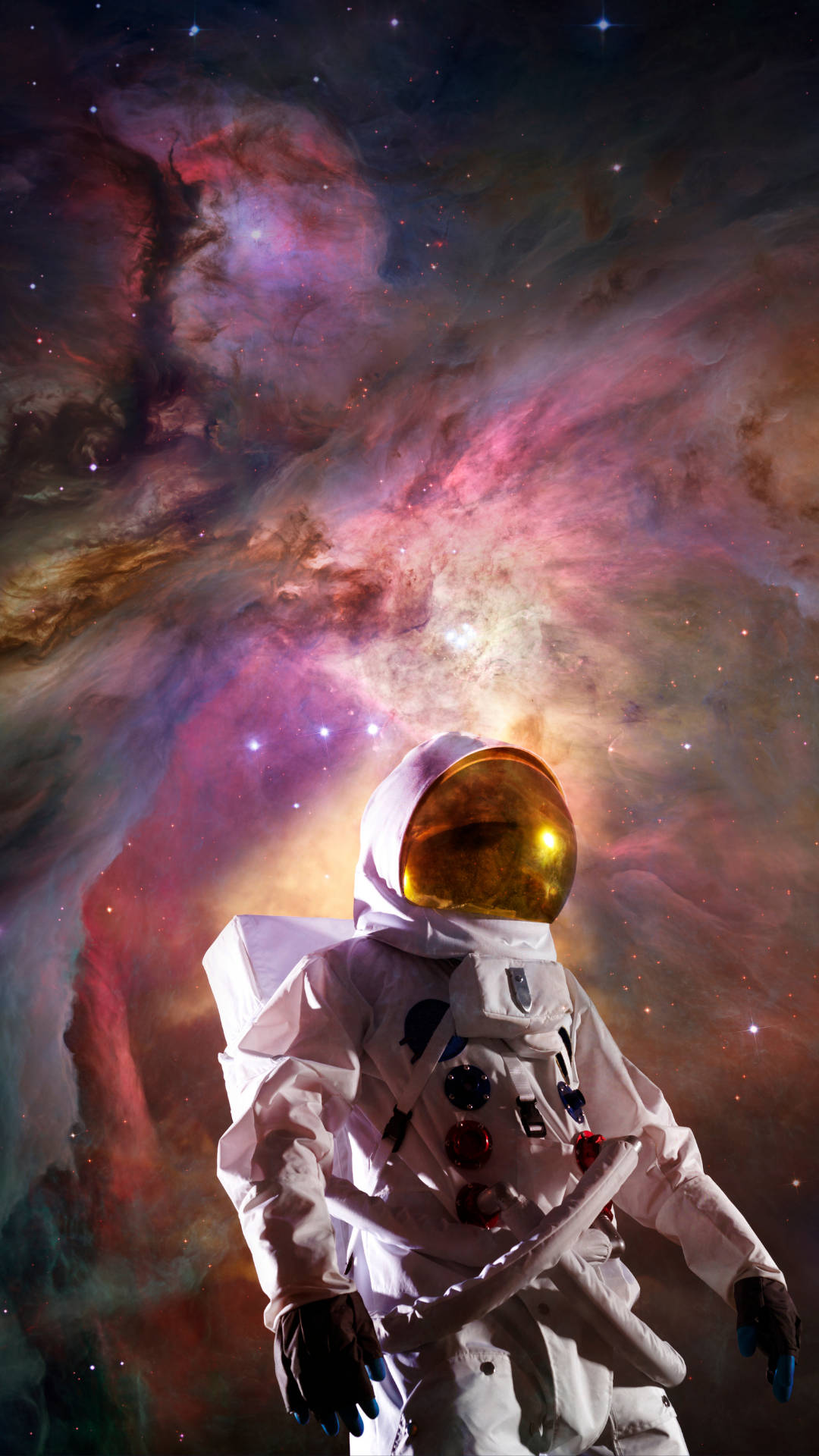 宇航員在紫色星雲中 壁紙 — 一名身穿白色太空衣的太空人站在一個散發粉紅、紫色和金色光芒的鮮豔宇宙星雲前。