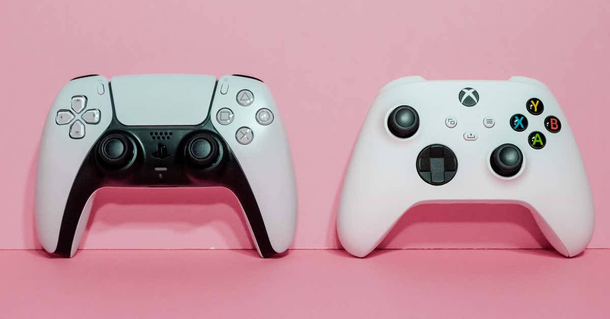 粉紅色表面上的兩個視頻遊戲控制器 PlayStation 和 Xbox