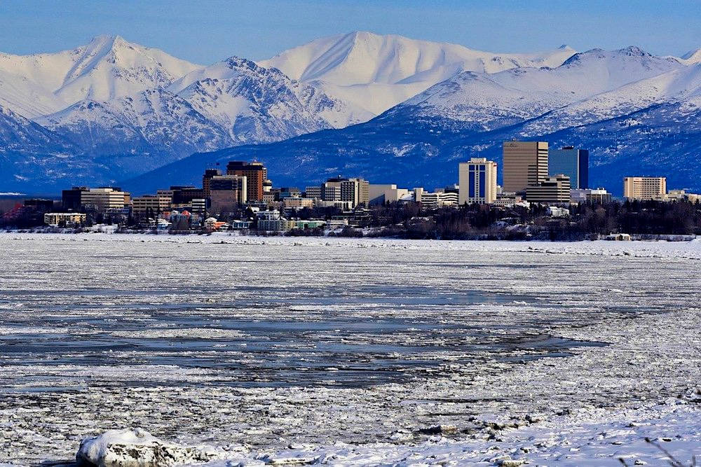 結冰的河流，背景有城市和積雪的山峰