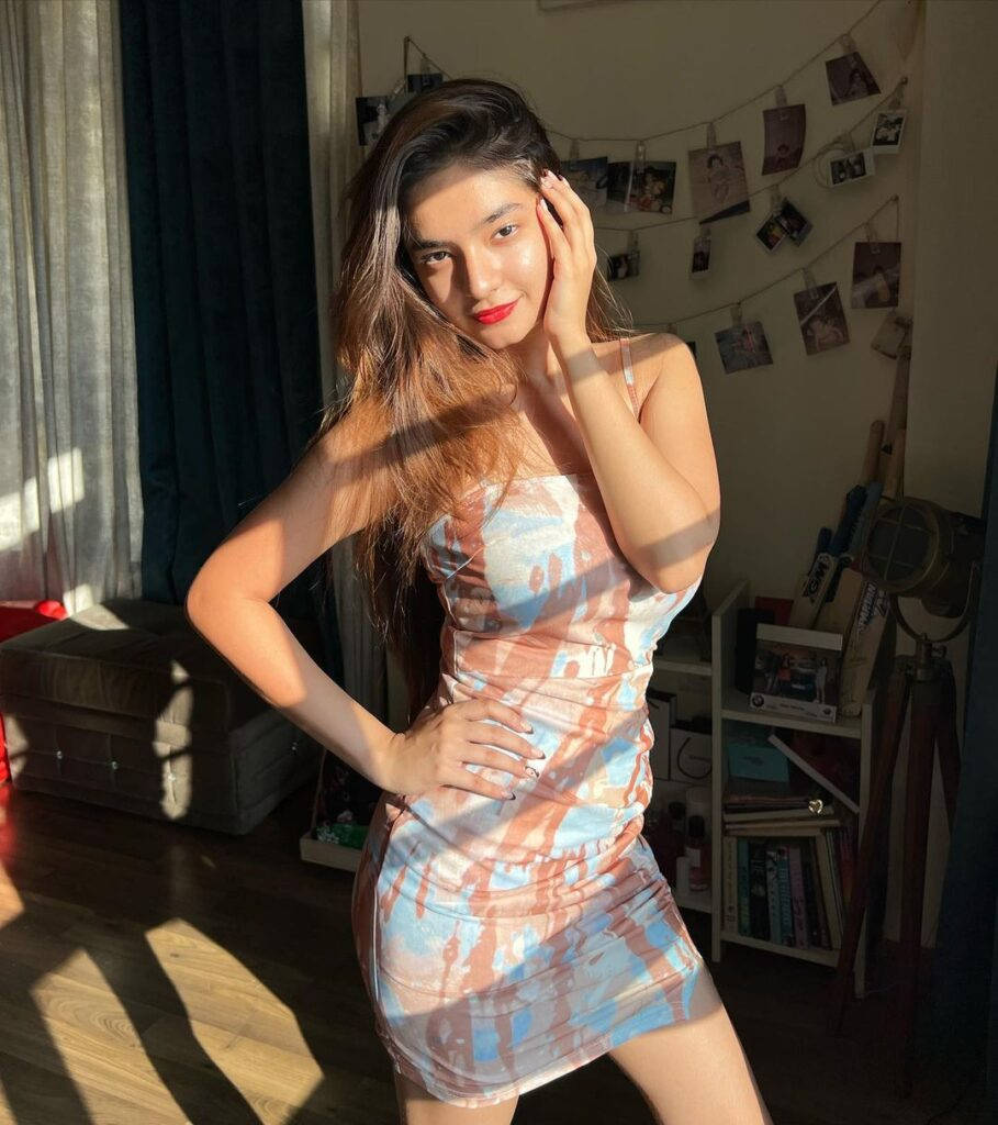 穿著紮染連衣裙的女性在陽光充足的房間裡擺姿勢，背景有照片繩裝飾。