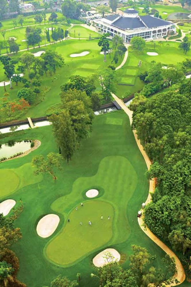 俯瞰高爾夫球手在充滿活力的綠色球場上打球，周圍有樹木和水景。