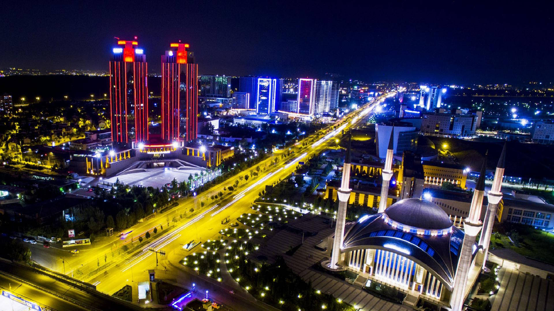 安卡拉市夜景 壁紙 — 從高空俯瞰充滿活力的城市景觀，閃爍的摩天大樓和一座宏偉的、帶有宣禮塔的燈光清真寺。