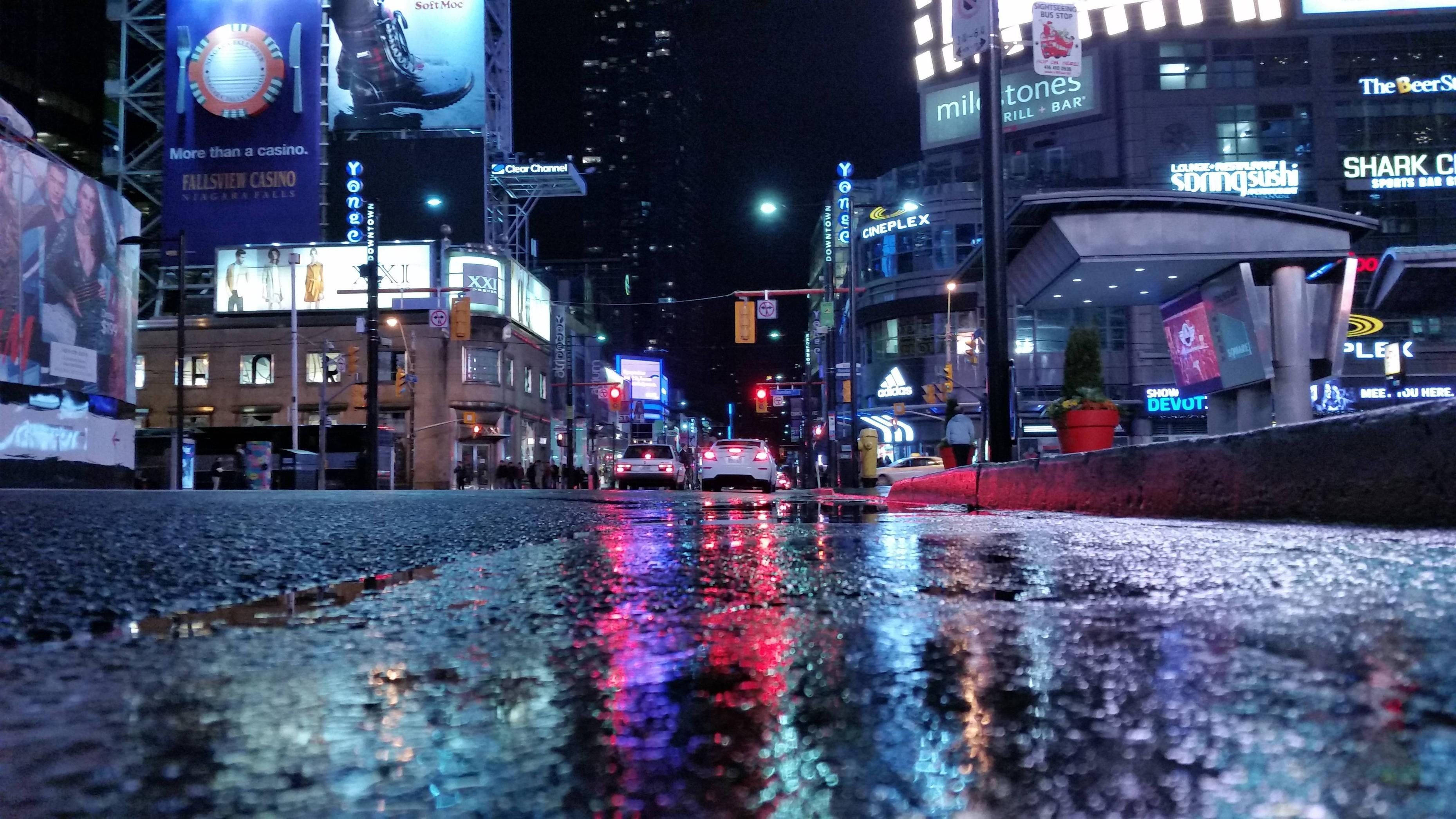 安大略多倫多街景夜間 壁紙 — 雨濕的夜晚城市街道反射著高聳建築物和發光廣告牌的霓虹招牌。