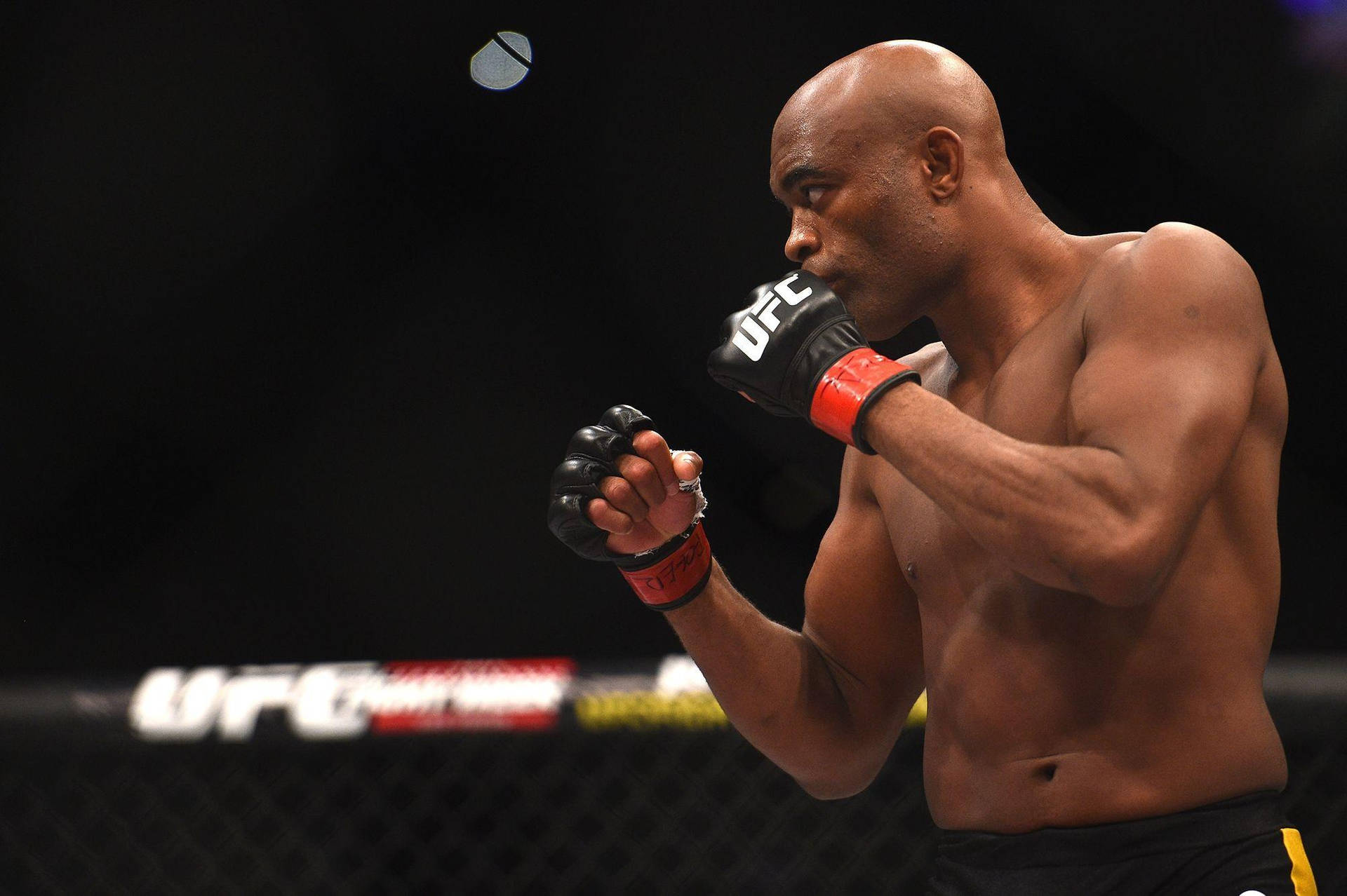 一名赤裸上身的MMA拳手在UFC八角籠內揮拳。