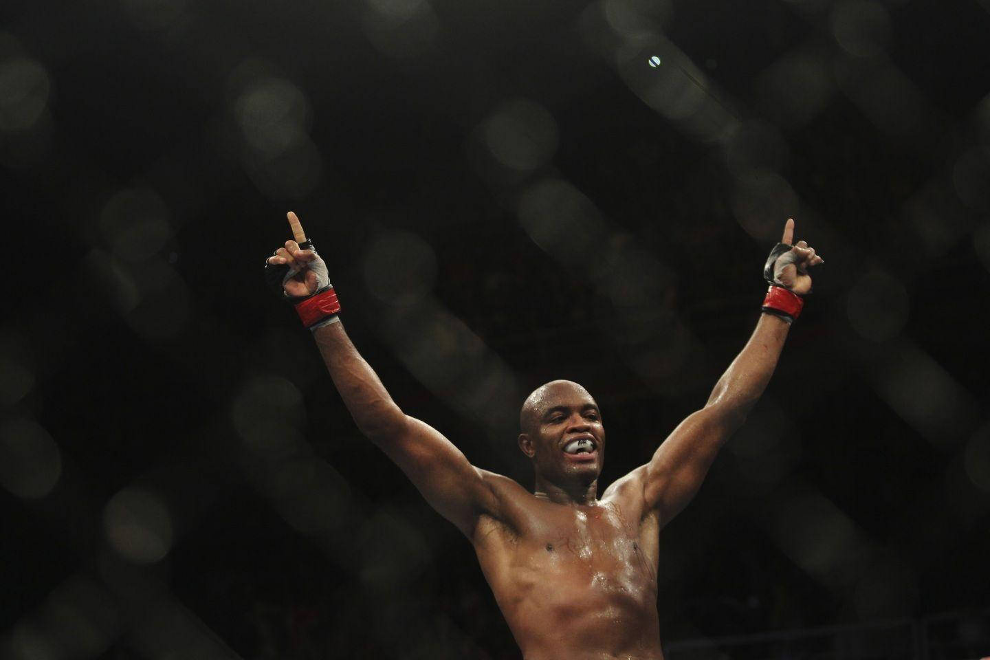 一位勝利的MMA拳手在黑暗的八角籠內舉臂歡呼。