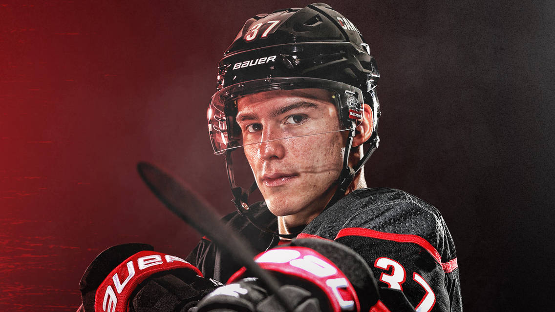 安德烈·斯維琴科夫 NHL 球衣照 壁紙 — 一位專注的曲棍球運動員身穿黑色和紅色裝備，在戲劇性的紅色和黑色背景下握著他的球桿。