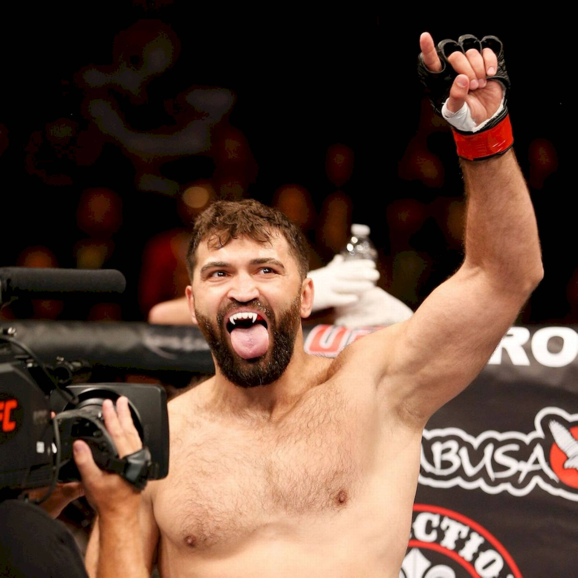 MMA拳手在八角籠中舉起拳頭並伸出舌頭慶祝勝利。