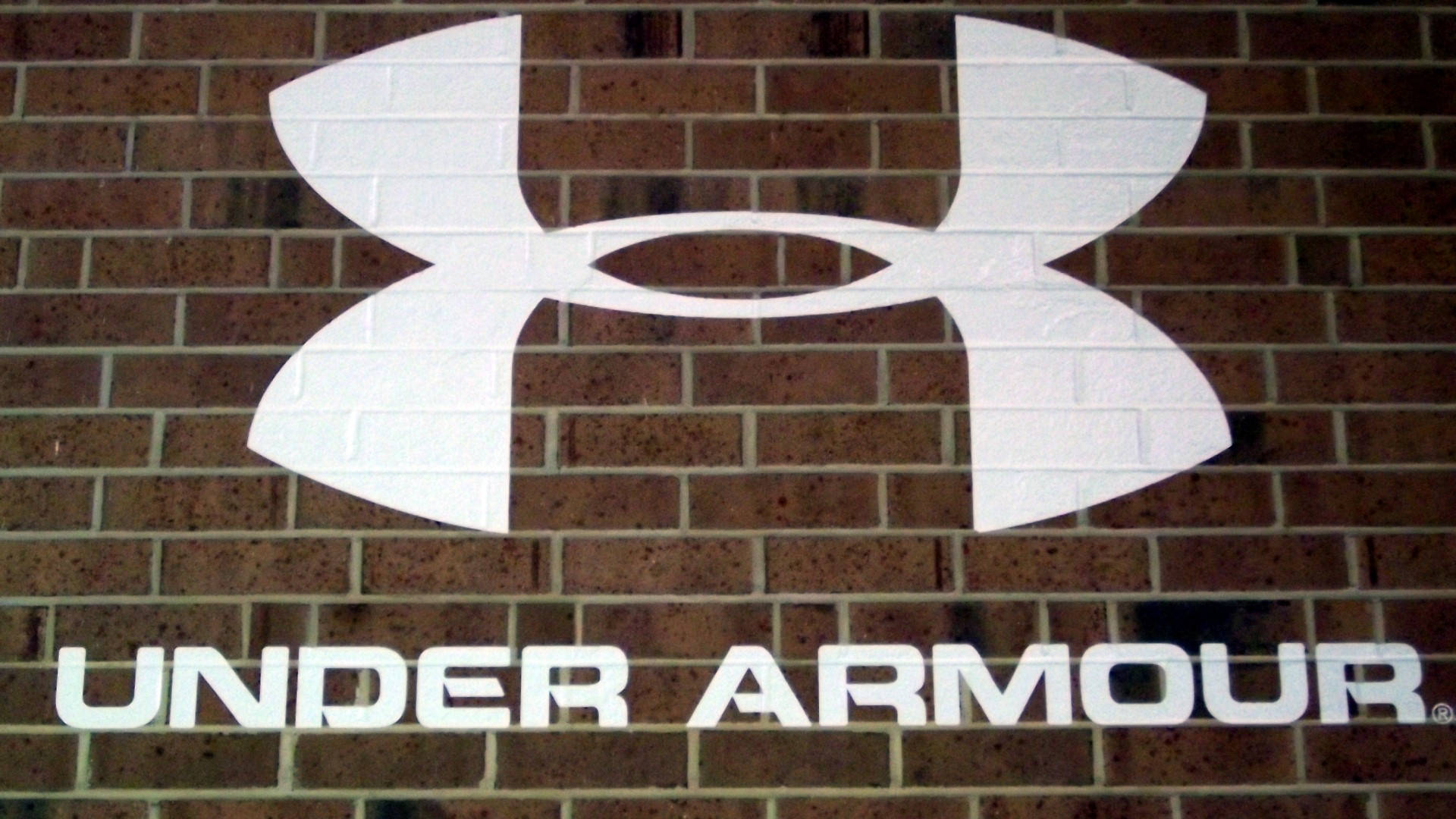 磚牆上的白色Under Armour標誌和文字。