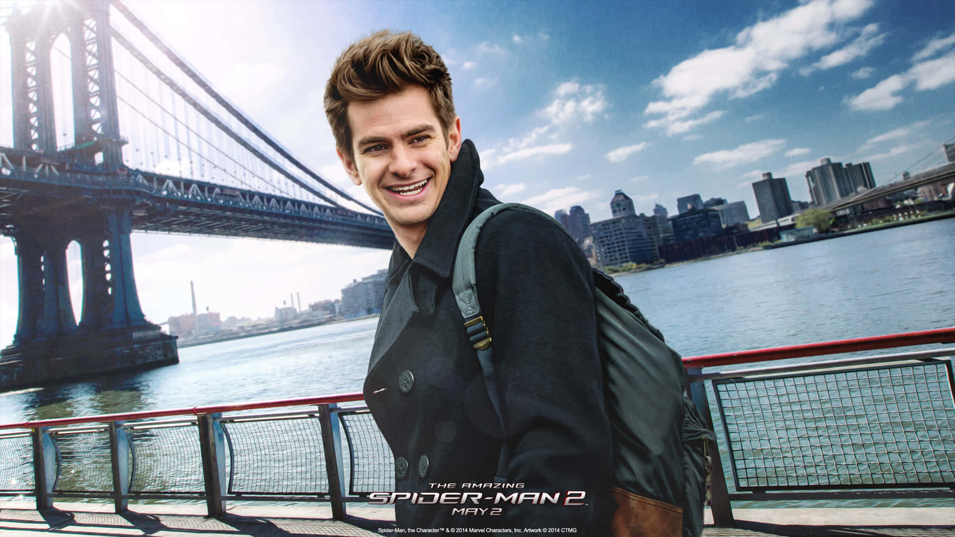 一個穿著深色外套和背包的男人在海濱微笑，背景是曼哈頓大橋和城市天際線。