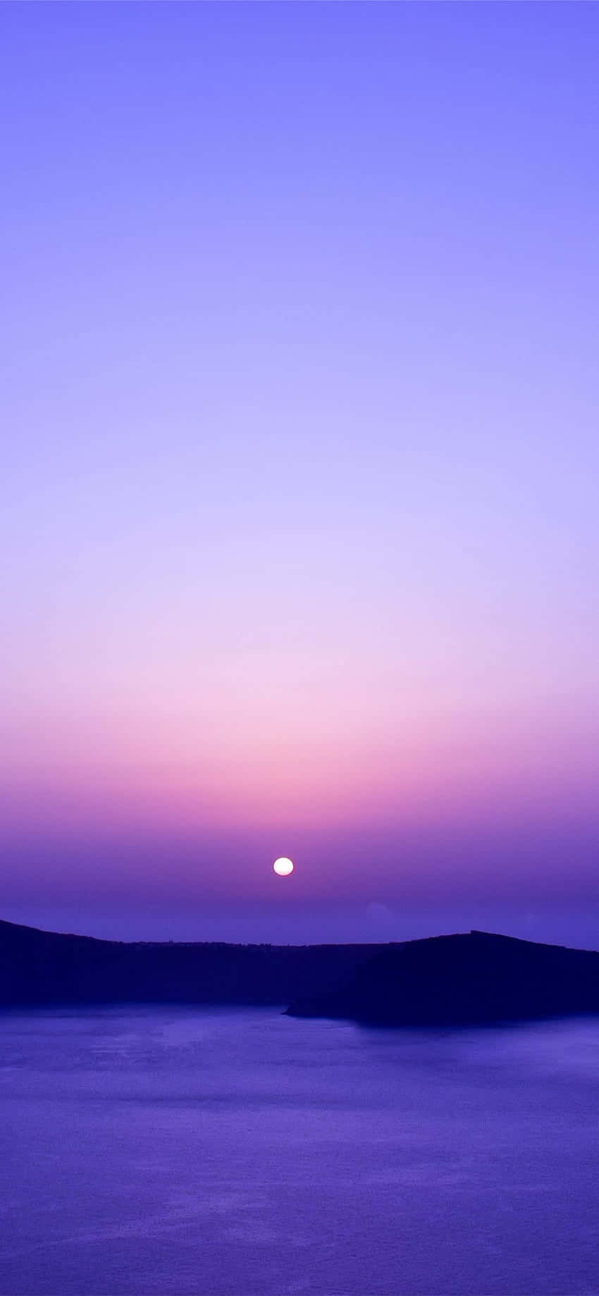 暮色中月亮在平靜的海面上升起，伴隨著紫色的天空和黑暗的懸崖。