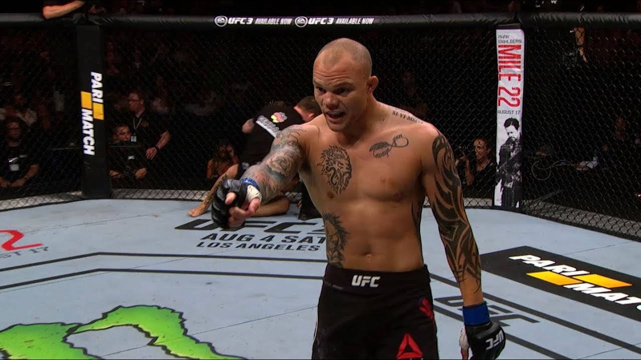 安東尼·史密斯指揮 壁紙 — 一位有紋身的UFC拳手在八角籠中慶祝勝利，對手則倒在擂台上。