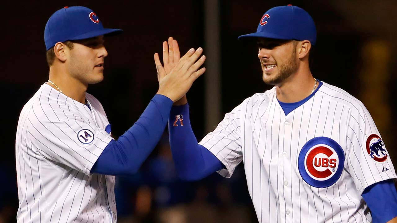 兩位身穿小熊隊球衣的棒球選手在夜間比賽中擊掌。