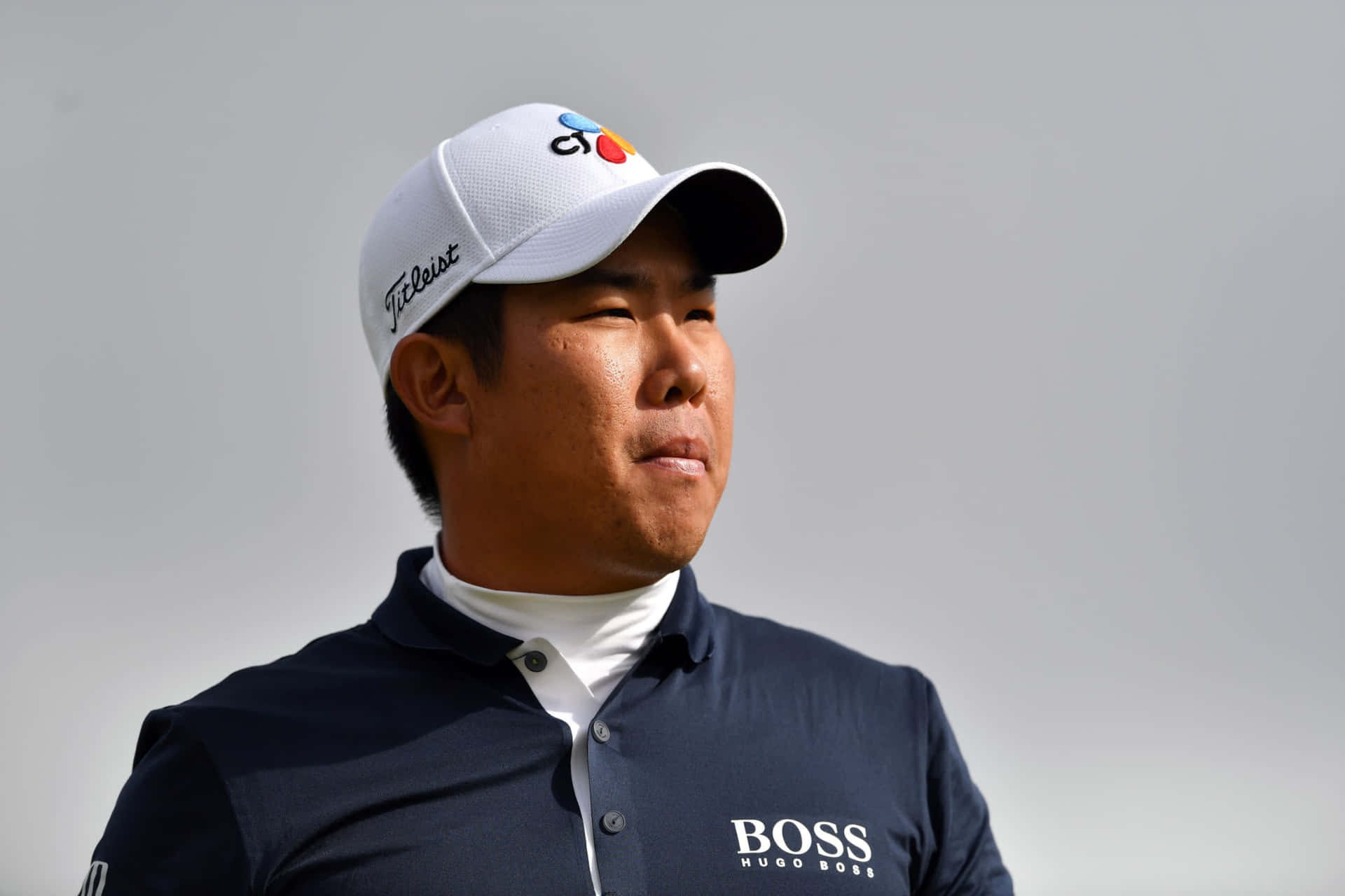 專業高爾夫球手戴著白色帽子和海軍藍 Hugo Boss 馬球衫。