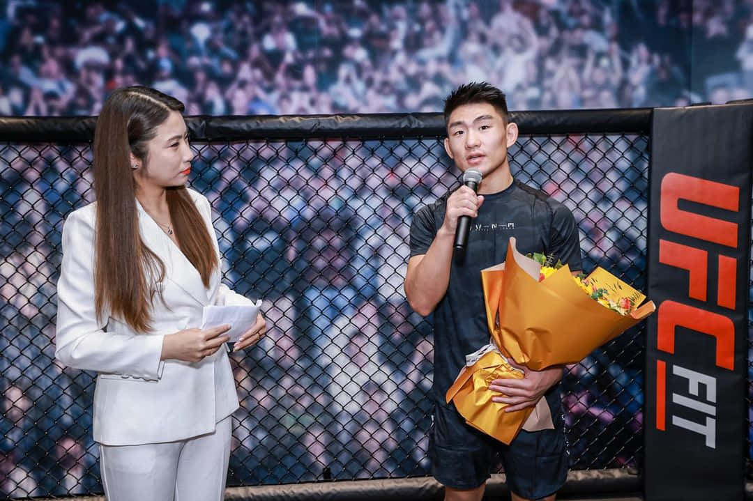 UFC拳手手持鮮花，在八角籠內與記者交談。
