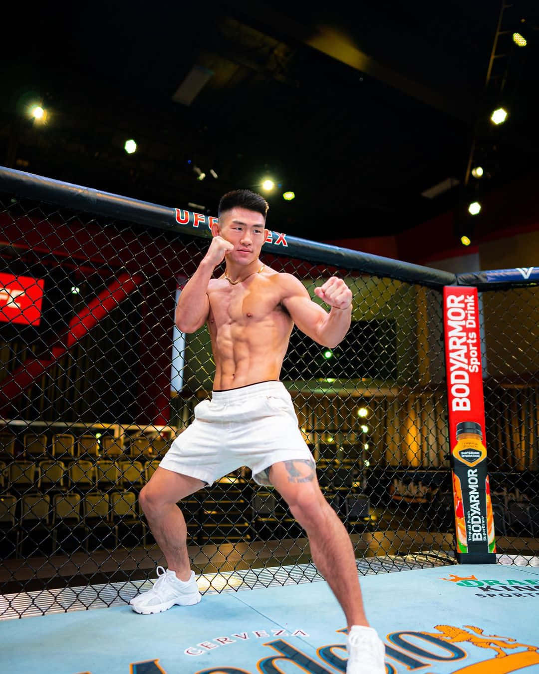 運動型拳手穿著白色短褲在UFC八角籠內擺姿勢。