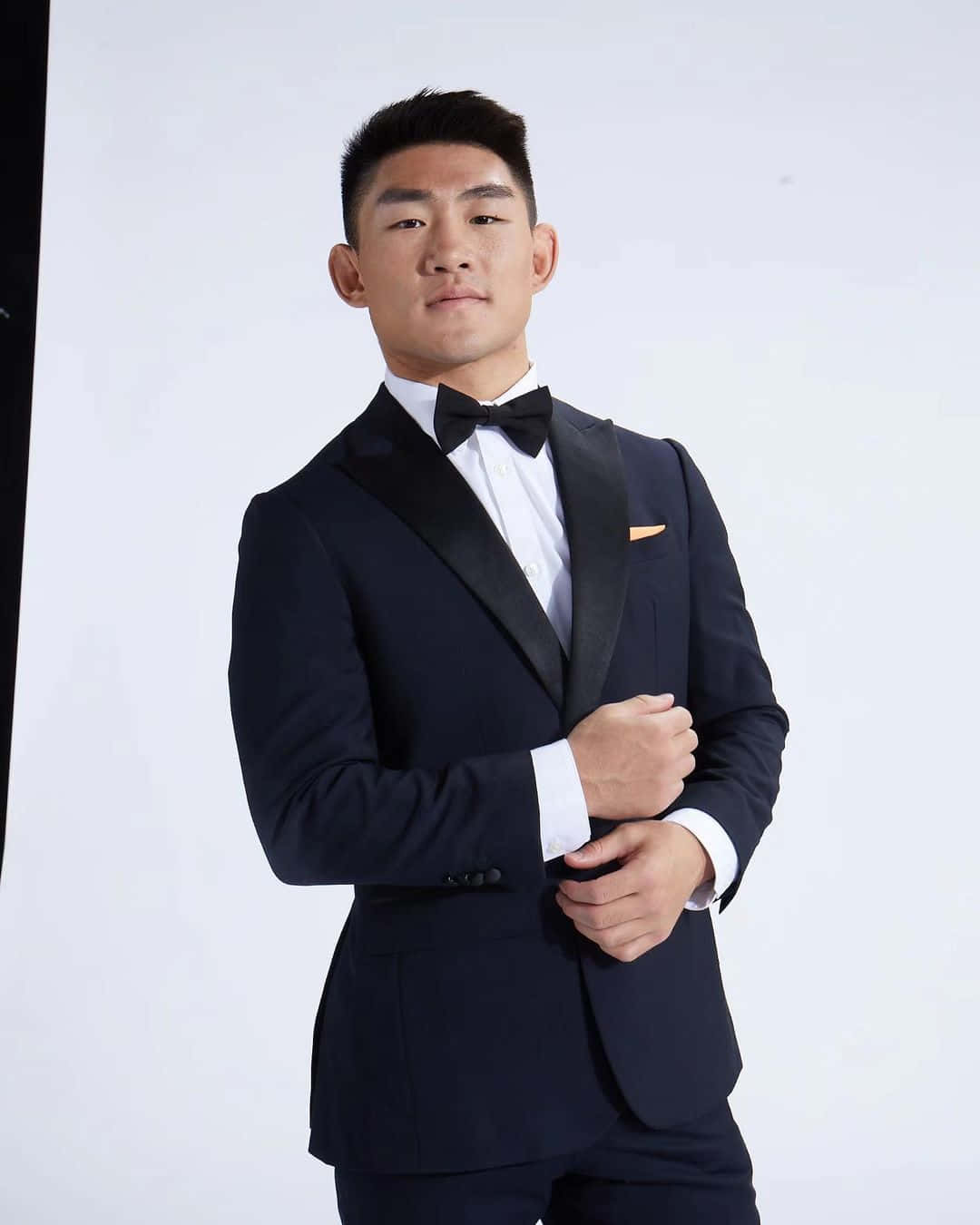 男士穿著黑色禮服同蝴蝶結喺影樓擺姿勢
