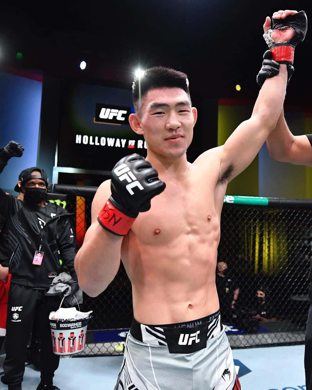 UFC拳手在八角籠內高舉手臂慶祝勝利。