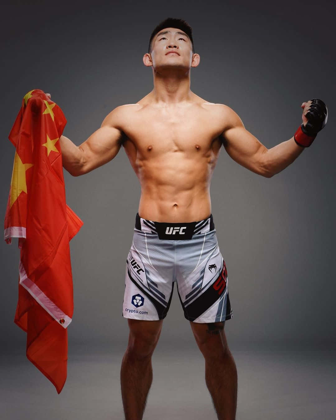 一位赤裸上身的男性拳手在工作室中手持中國國旗慶祝勝利。