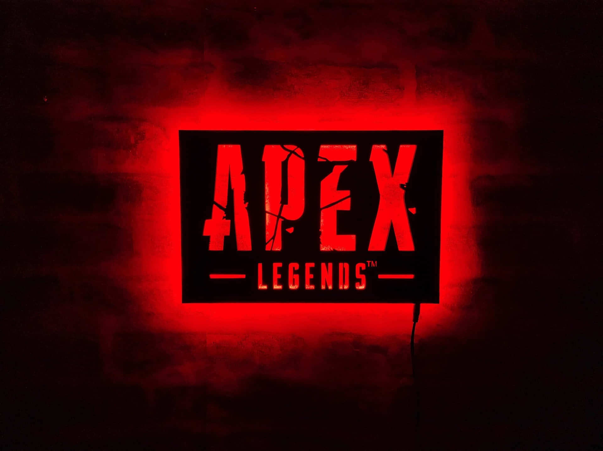 黑暗房間中磚牆上發光的紅色Apex Legends標誌。