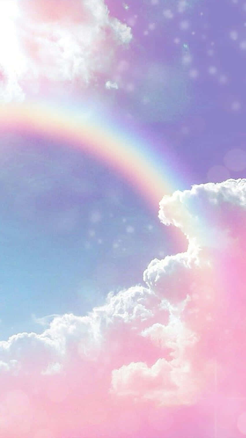 完美佈置的羽翼：地平線上的彩色美學雲朵 壁紙 — 夢幻的粉彩天空，柔和的彩虹拱在沐浴在粉紅和紫色光線中的蓬鬆雲朵上。