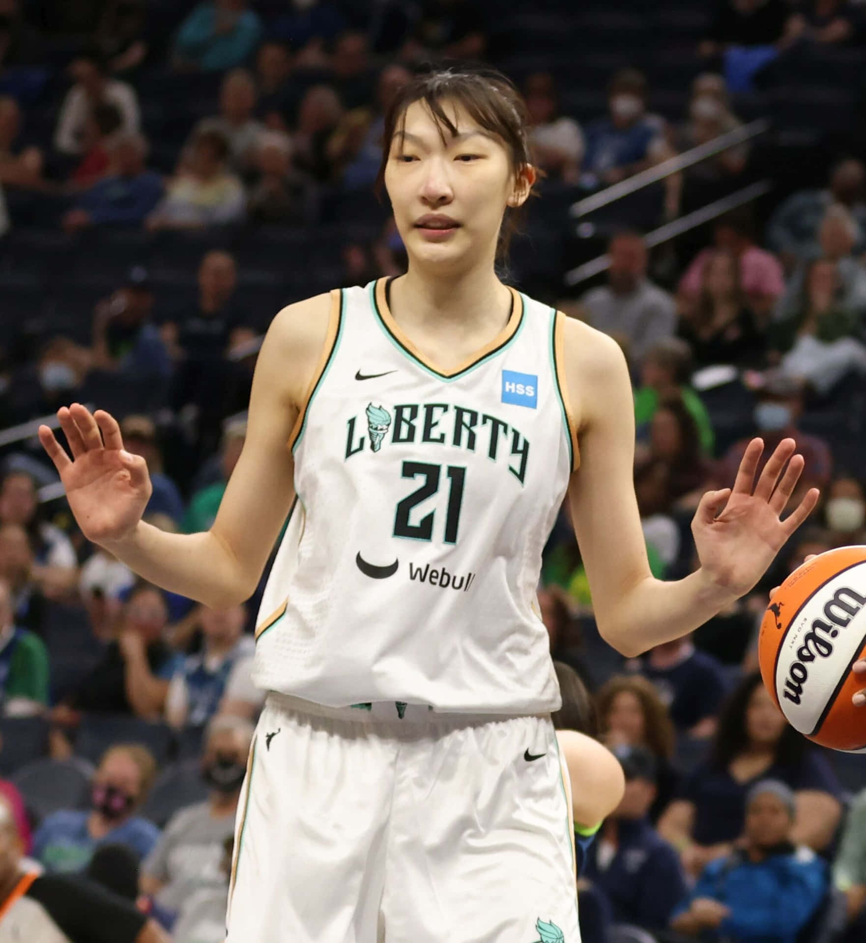 身穿白色自由人隊球衣的女籃球員在比賽中舉手拿球。