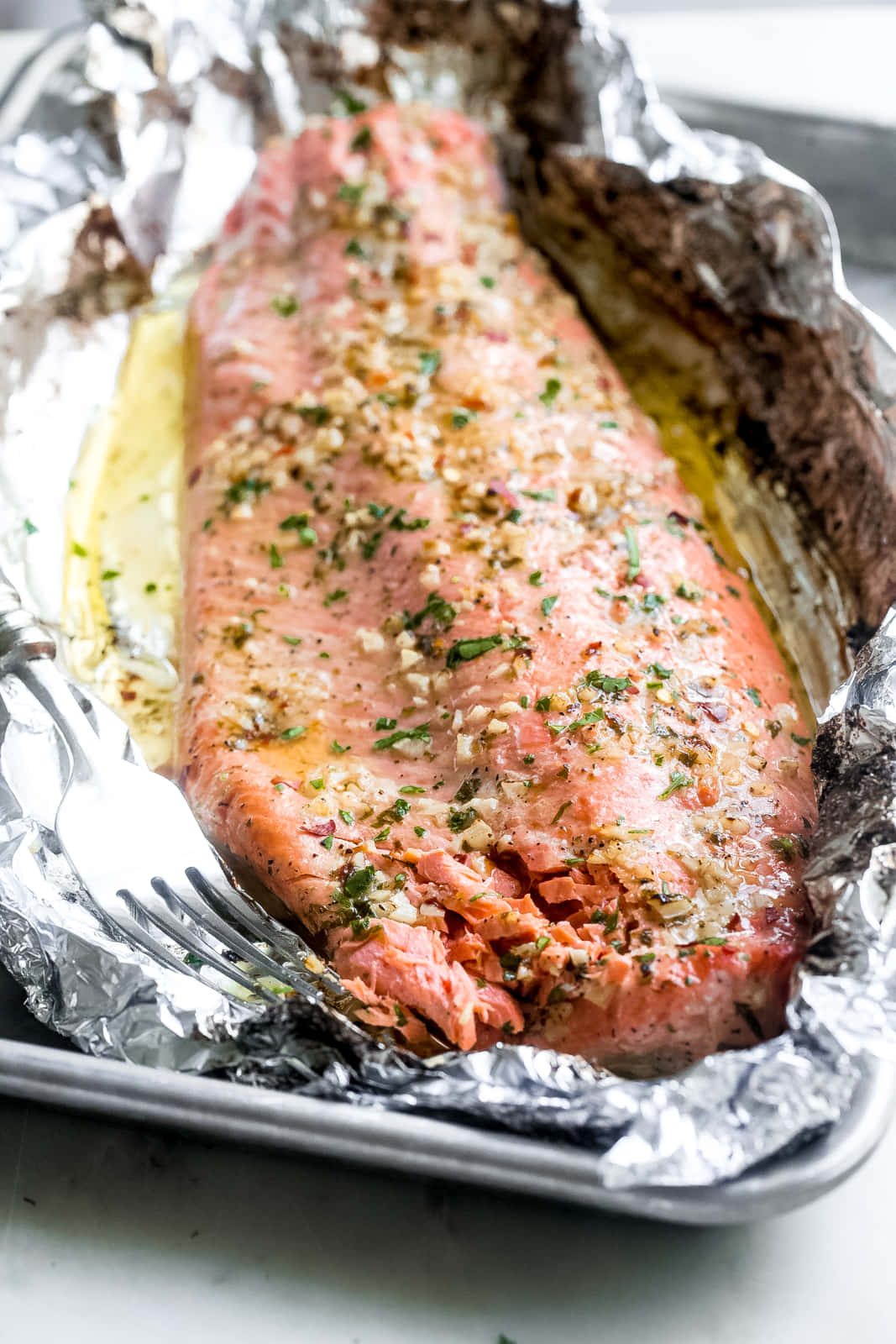 Salmon 桌布 壁紙 — 完美烹調的三文魚柳，以香草和大蒜調味，放在錫紙上，置於烤盤中，旁邊放著叉子。