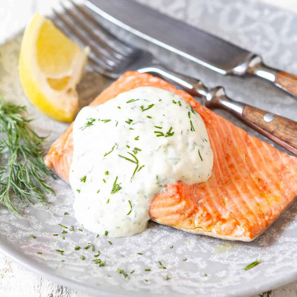 Salmon 桌布 壁紙 — 完美烹調的三文魚柳，配上奶油蒔蘿醬，並以新鮮蒔蘿和檸檬角裝飾，置於紋理盤上。