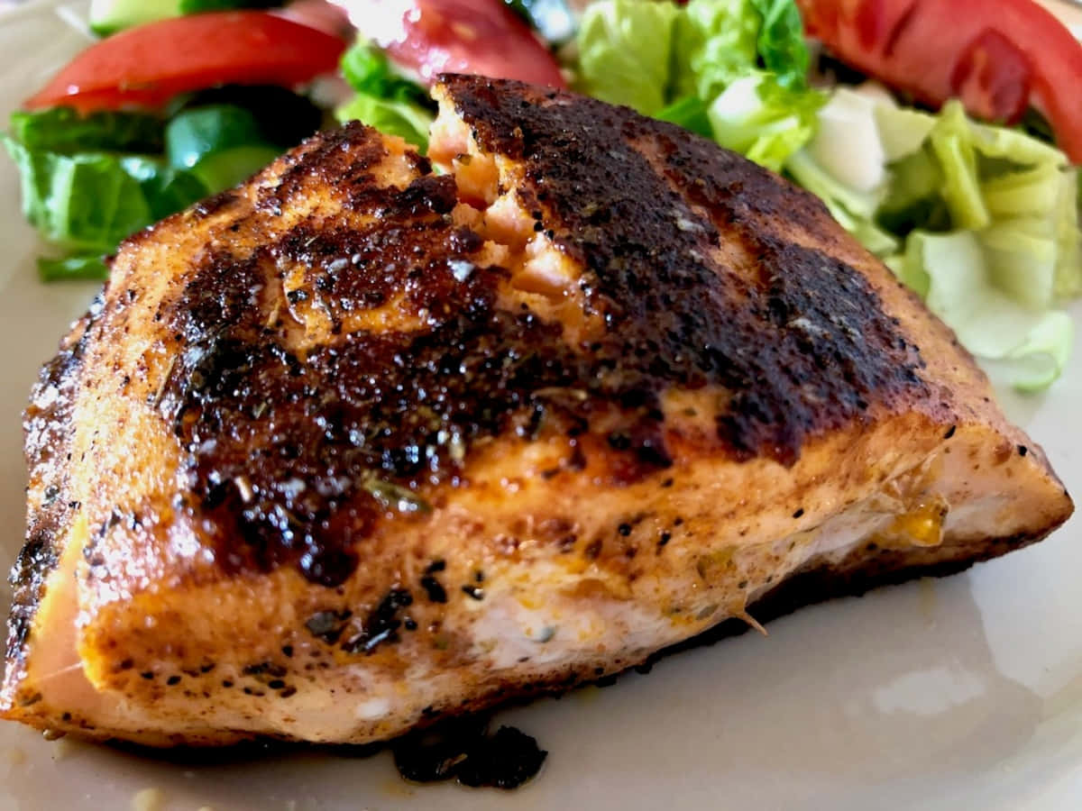 Blackened Chicken 桌布 壁紙 — 完美煎封的三文魚柳，魚皮香脆，放在白色碟上的新鮮生菜番茄沙律上。