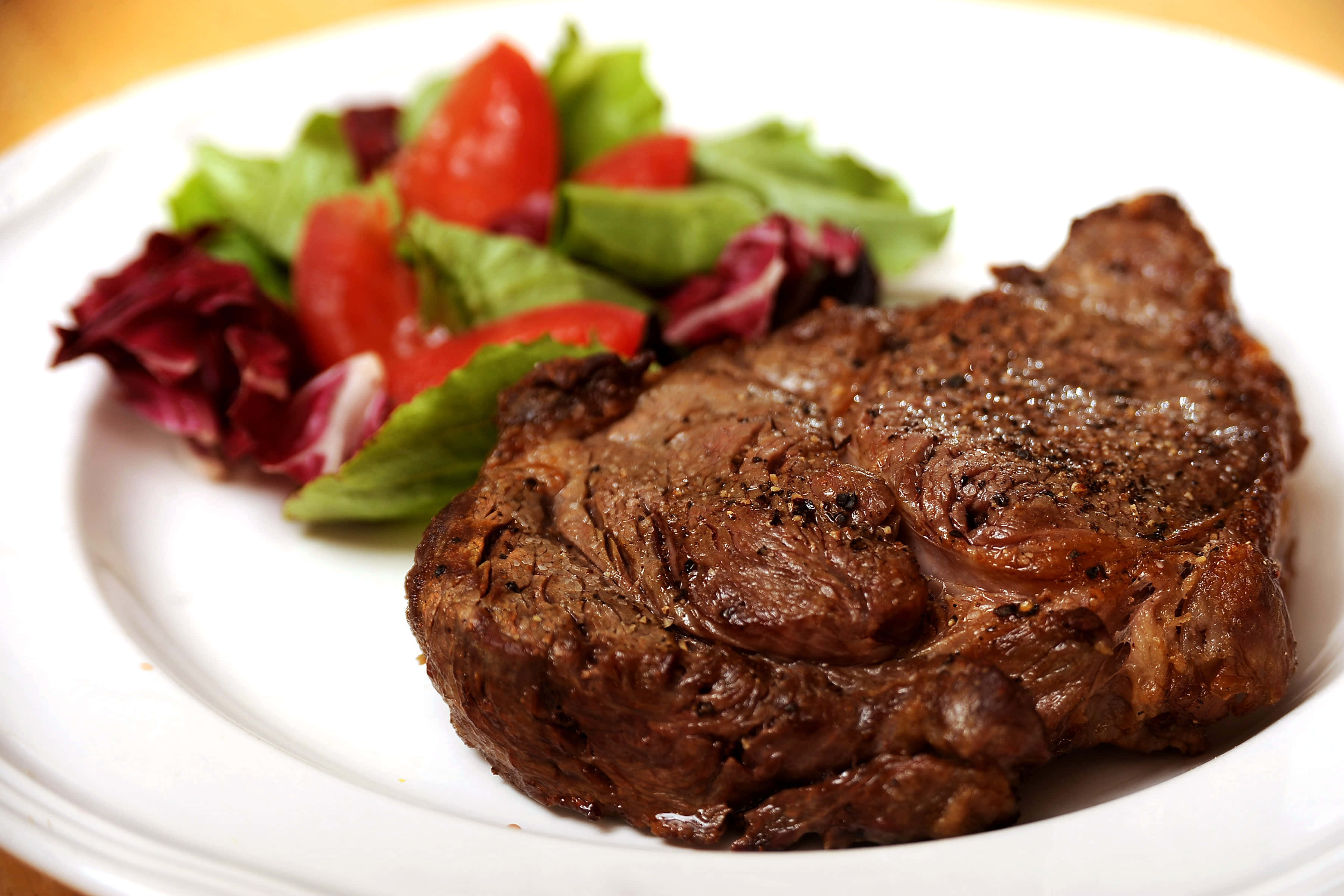 meat 桌布 壁紙 — 完美煎烤的牛排，外皮酥脆，搭配新鮮沙律，盛於白色餐盤上。