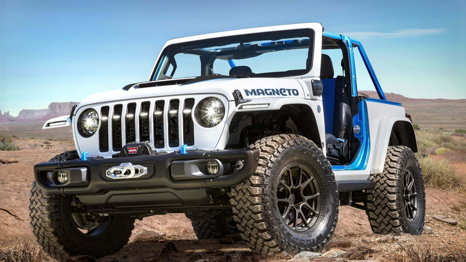 白色和藍色的定制Jeep Wrangler在日落時停放在沙漠岩石上。