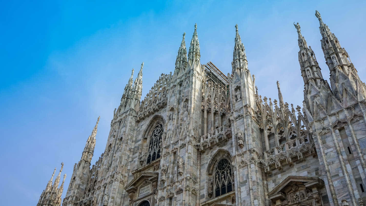 Gothic Architecture 桌布 壁紙 — 宏偉的哥德式大教堂，擁有精緻的尖塔和石雕，在清澈的藍天下雄偉地聳立。