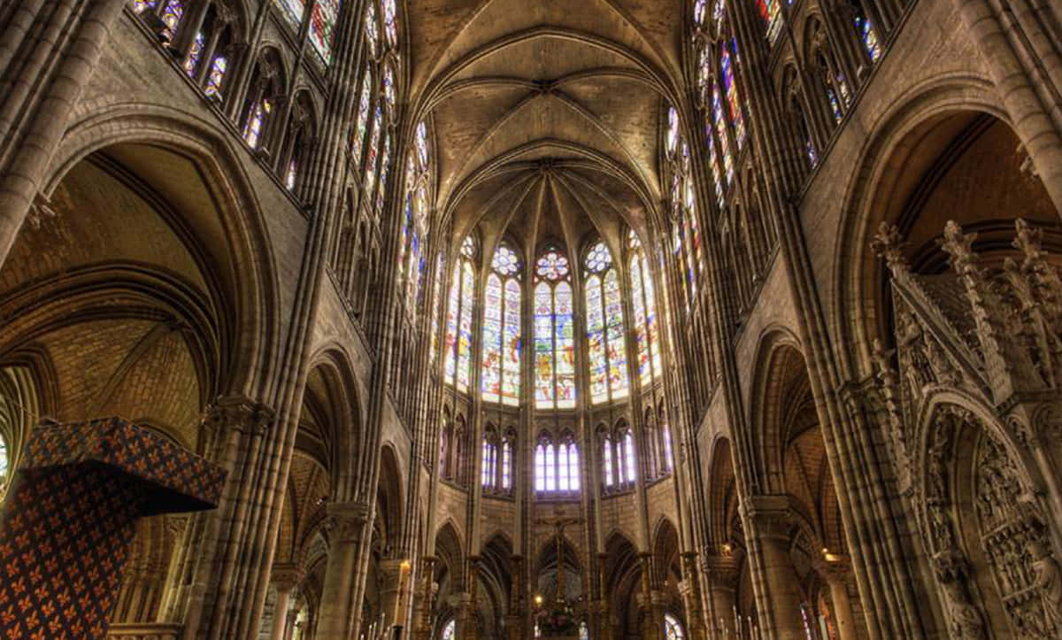 Gothic Architecture 桌布 壁紙 — 宏偉的哥德式大教堂內部，高聳的石拱頂和色彩繽紛的彩繪玻璃窗投射出多彩的光線。