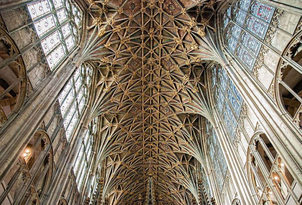 Gothic Architecture 桌布 壁紙 — 宏偉的哥德式大教堂天花板，帶有複雜的扇形拱頂和彩色玻璃窗，沐浴在自然光中。