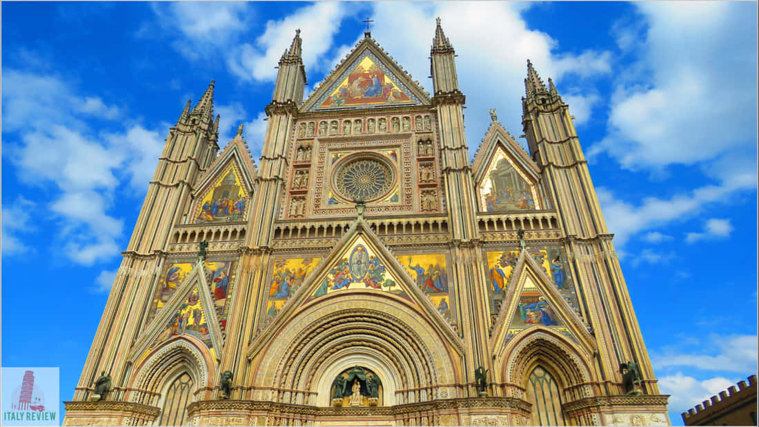 Gothic Architecture 桌布 壁紙 — 宏偉的哥德式大教堂正面，金色馬賽克和尖塔在藍天白雲下聳立。