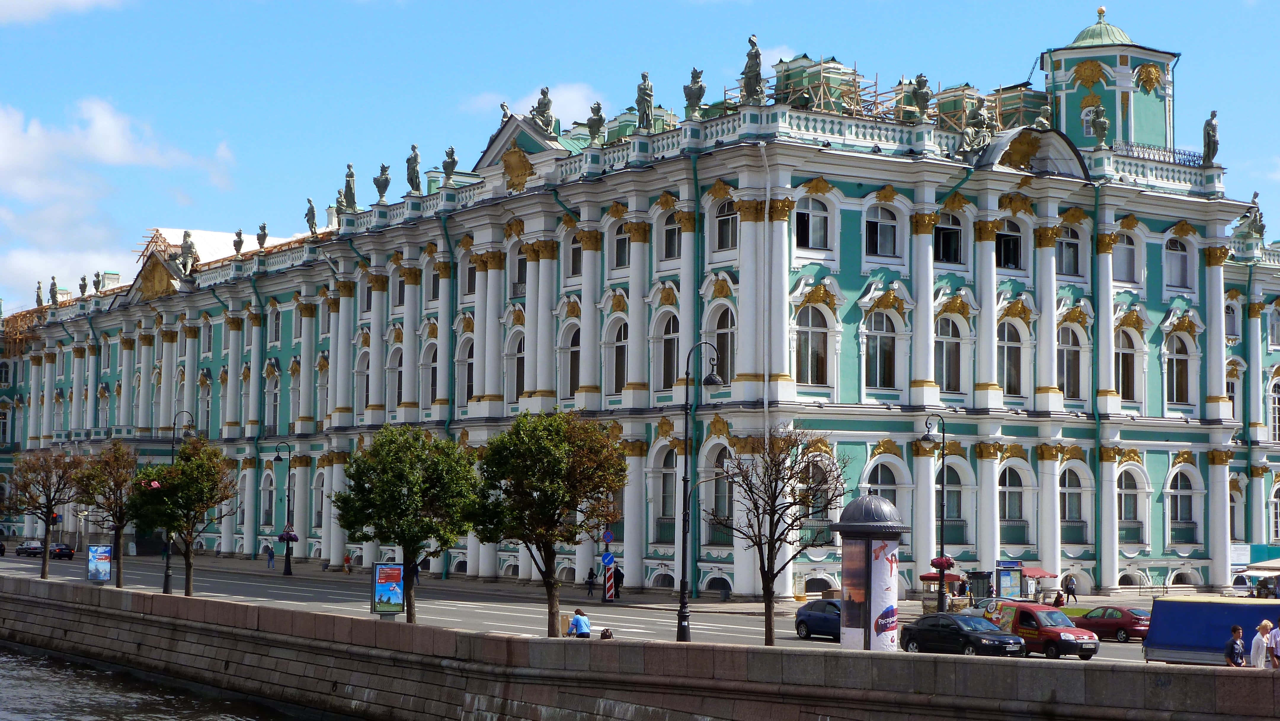 Museums 桌布 壁紙 — 宏偉的新古典主義建築，帶有藍綠色和金色點綴，矗立在河邊，天空清澈湛藍。