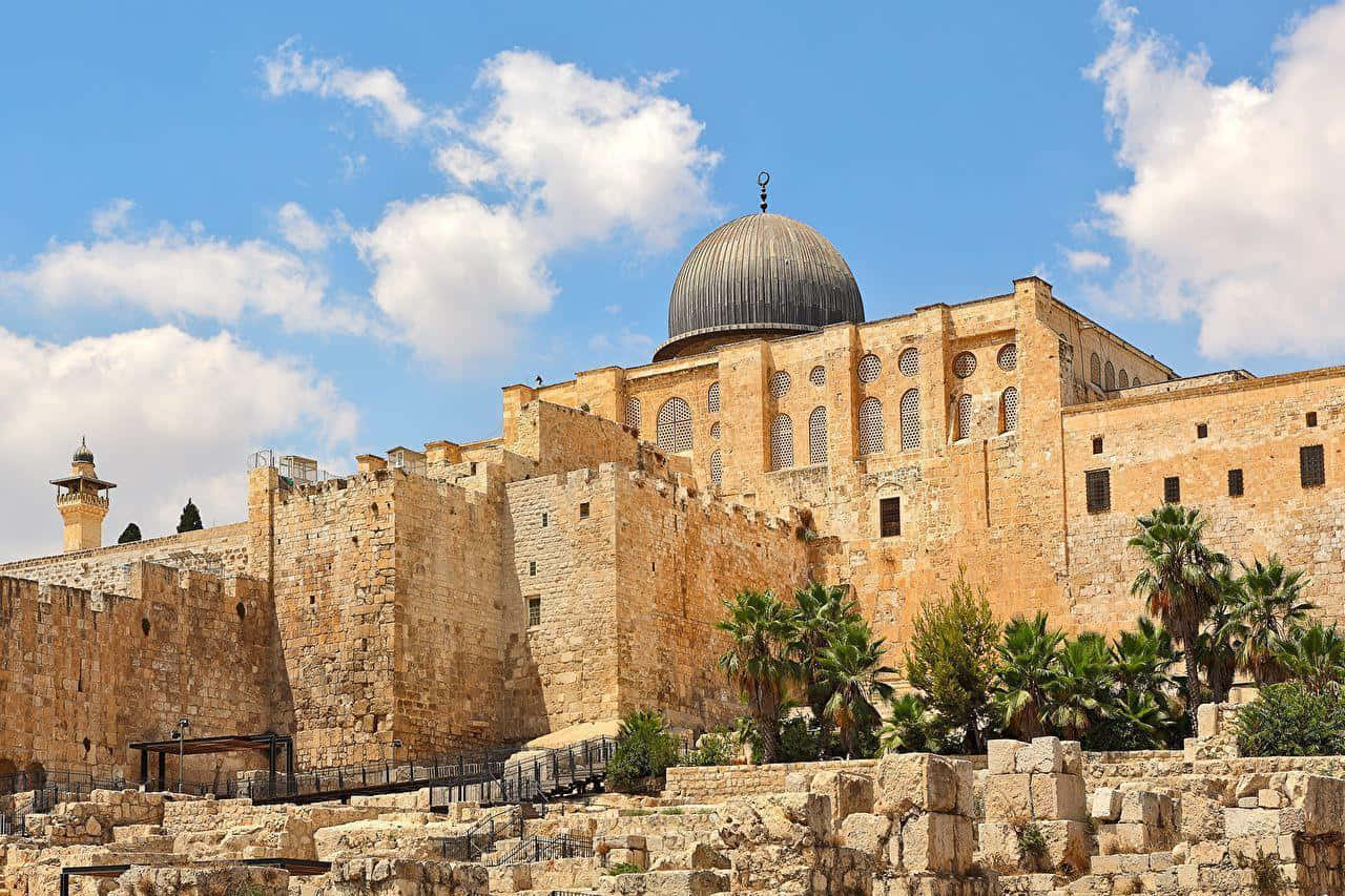 Israel 桌布 壁紙 — 宏偉的石造清真寺，擁有標誌性圓頂和宣禮塔，在明亮的藍天、蓬鬆雲朵和棕櫚樹的映襯下。