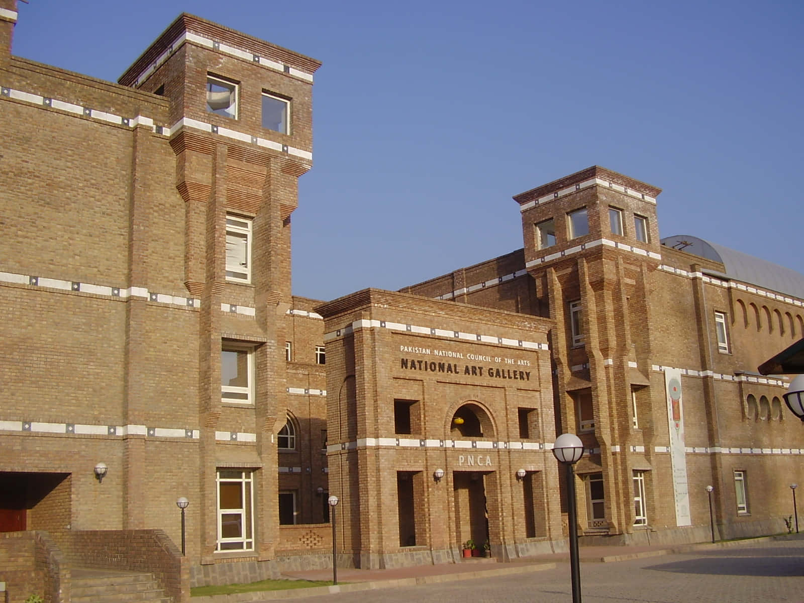Pakistan 桌布 壁紙 — 宏偉的磚造國家美術館建築，在清澈藍天下，擁有對稱塔樓和拱形入口。