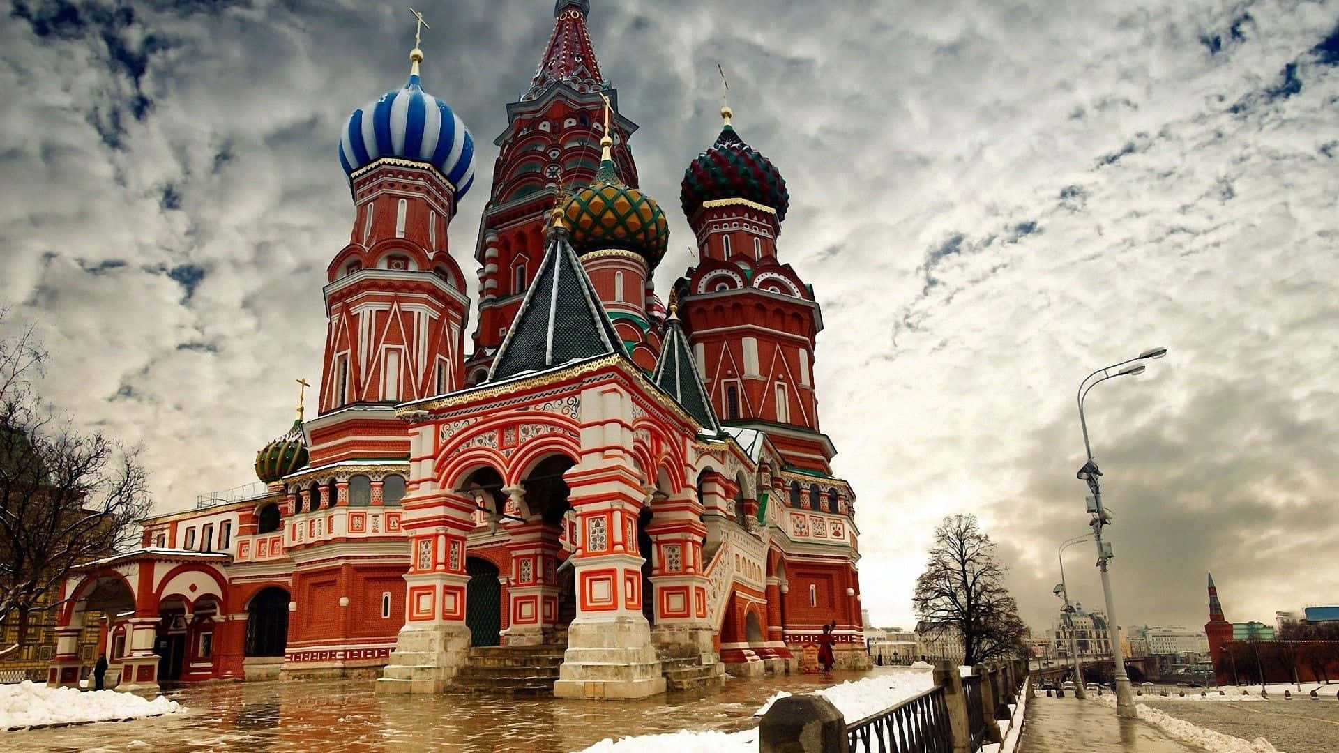 Russia 桌布 壁紙 — 宏偉的紅白相間聖瓦西里主教座堂，帶有色彩繽紛的洋蔥形圓頂，矗立在戲劇性的多雲天空下，地面積雪。