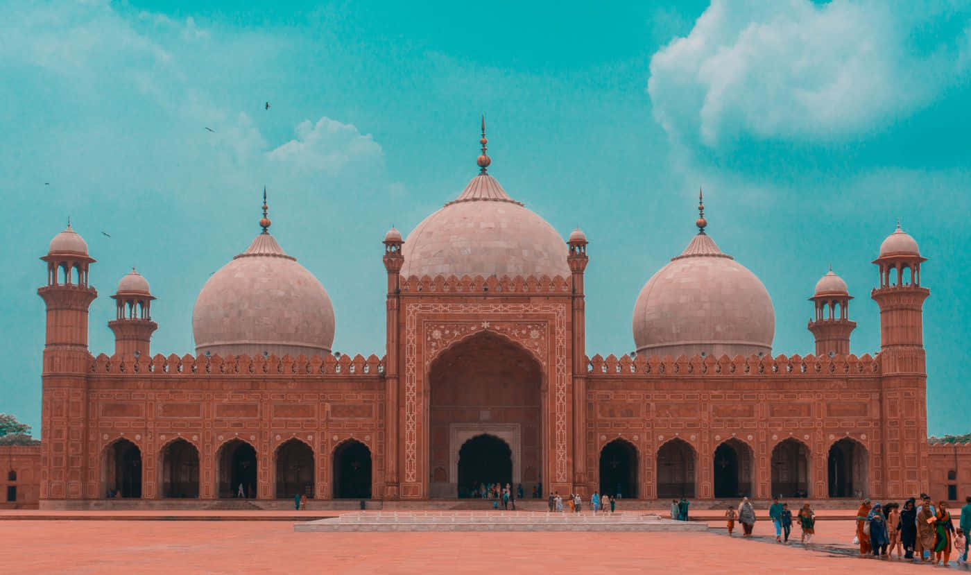 Pakistan 桌布 壁紙 — 宏偉的紅色砂岩清真寺，擁有圓頂和宣禮塔，在充滿活力的藍綠色天空下，點綴著散落的雲朵。