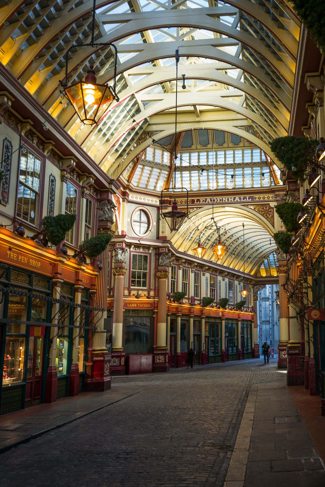Diagon Alley 桌布 壁紙 — 宏偉的維多利亞式拱廊，拱形玻璃天花板和溫暖的燈籠照亮了鵝卵石步道，兩旁是華麗的商店。