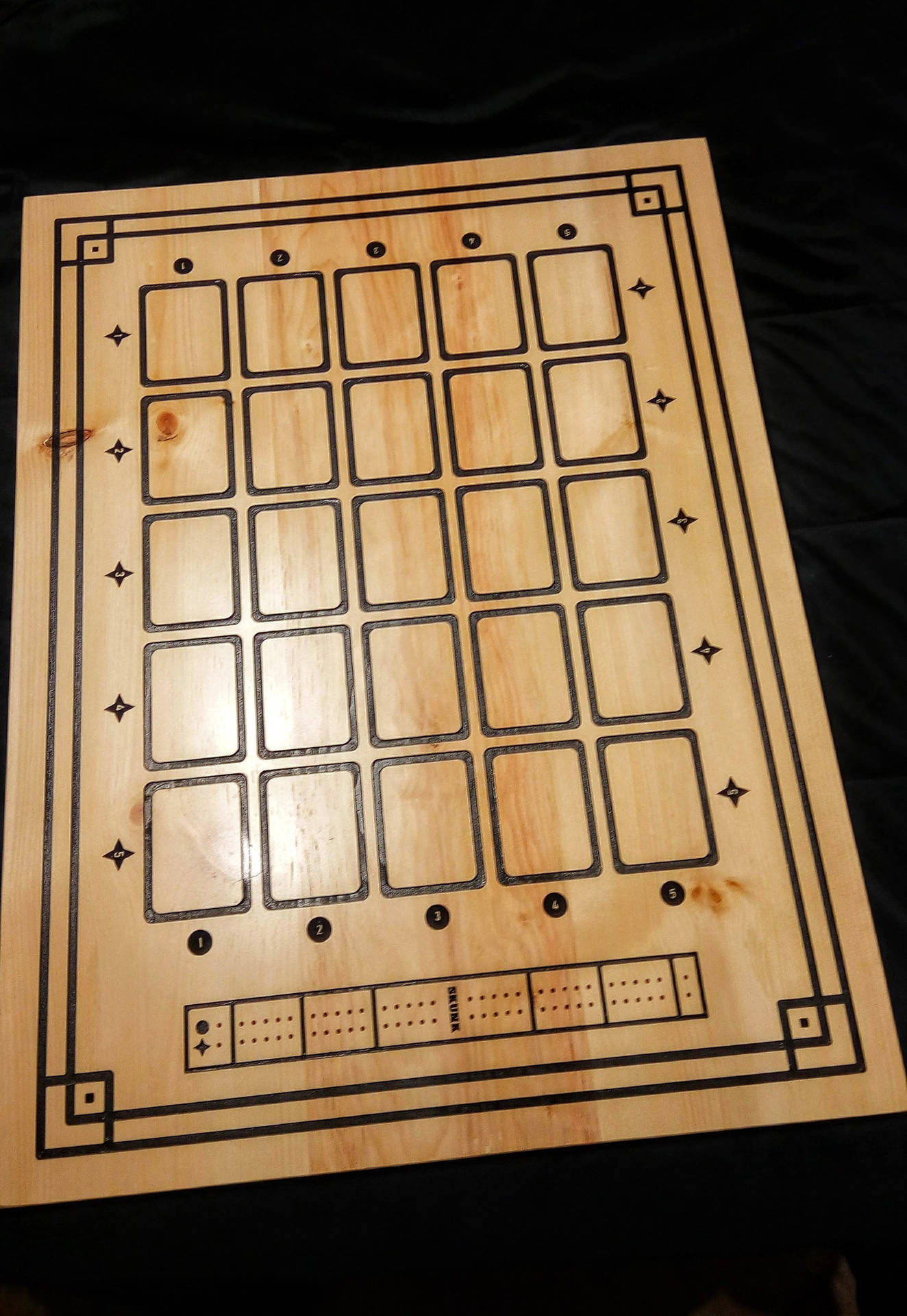 一個木製克里比奇棋盤，在深色背景上帶有黑色蝕刻線條和星星圖案。