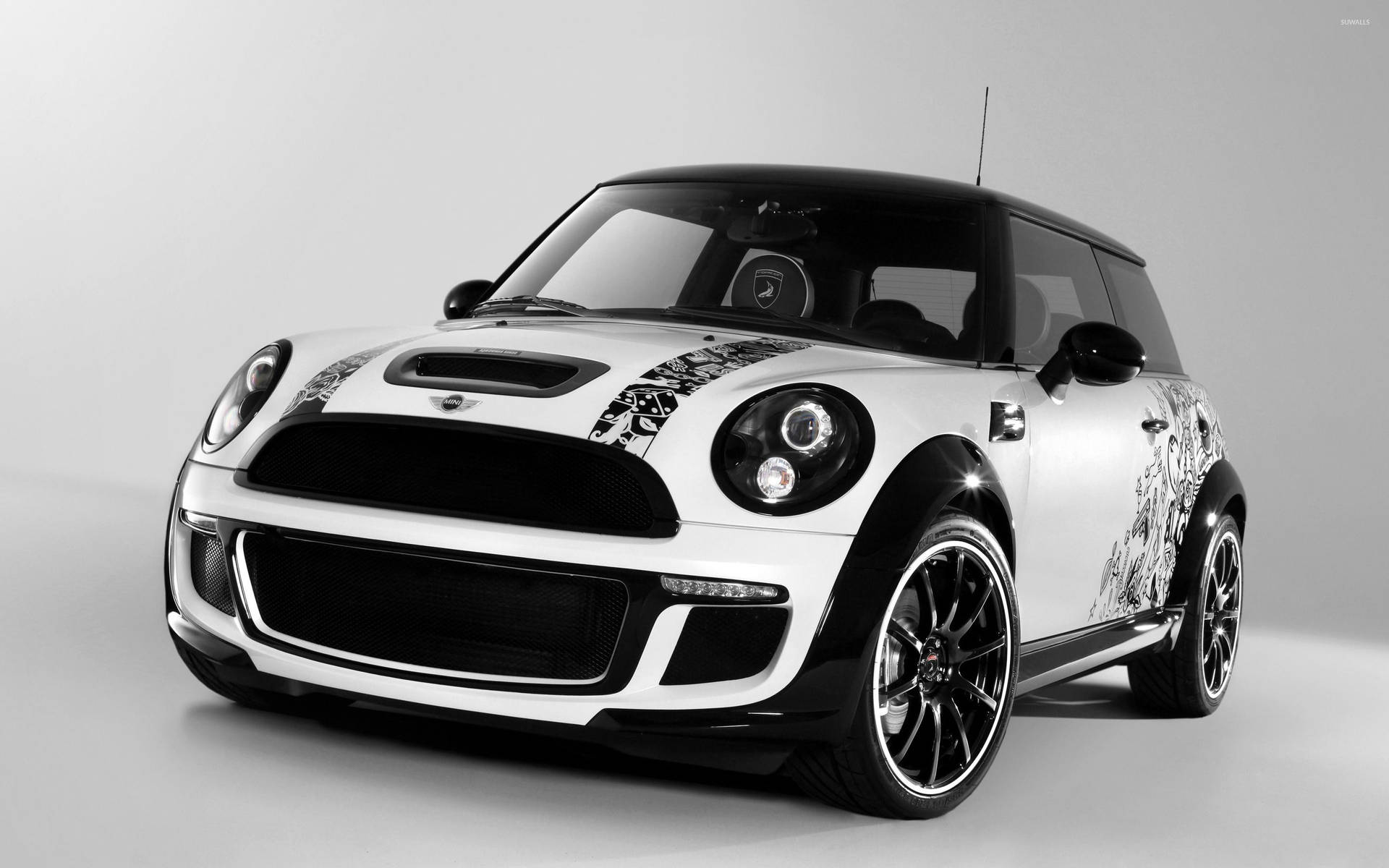 白色MINI Cooper，帶有黑色點綴和定制圖形，在工作室環境中。