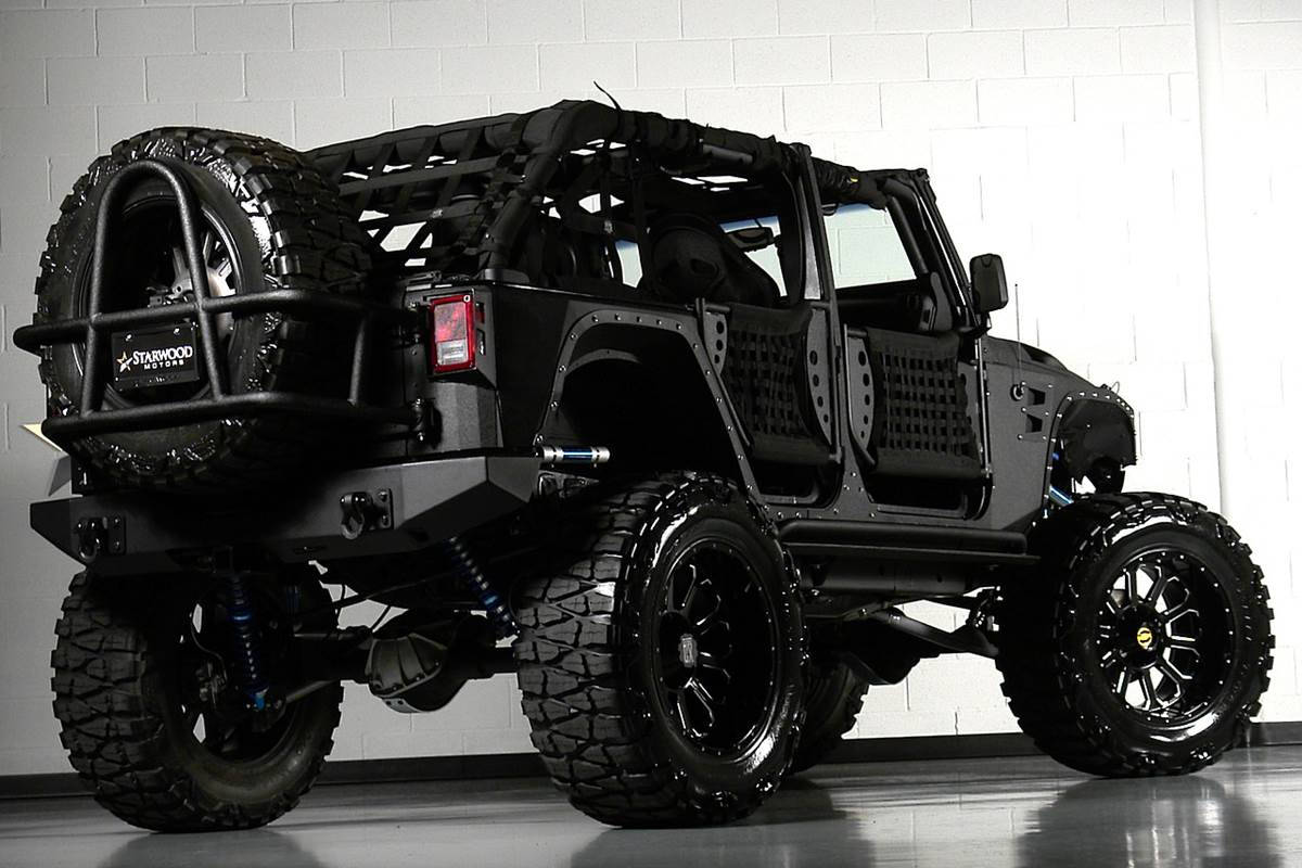 白色磚砌車庫中的定制黑色越野Jeep，帶有大輪胎。